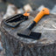 Ascia Fiskars X7 con manico arancione e nero, posata su un ceppo di legno, ideale per il campeggio e le attività all'aperto, con custodia protettiva. Strumento resistente e leggero per taglio e spacco di legna.